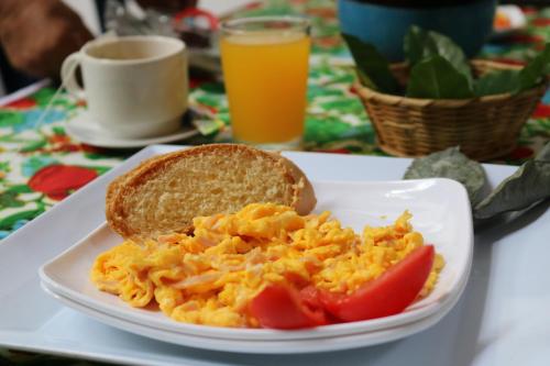 Un plato de huevos revueltos y una rebanada de pan con tomate. en Hotel Colonial - Honda -, en Honda