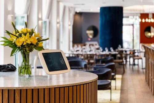 a tablet sitting on a table with a vase of flowers at Airedale Boutique Suites in Auckland
