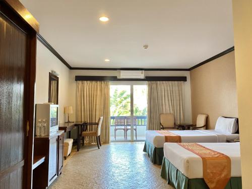 a hotel room with two beds and a desk at Golden Pine Beach Resort in Pran Buri