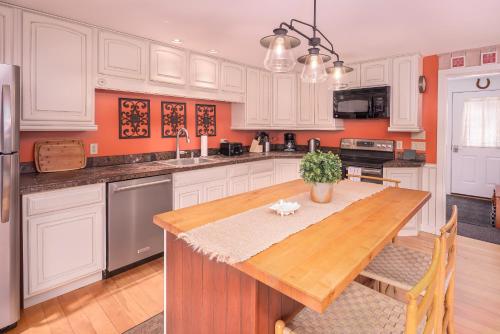 a kitchen with white cabinets and a wooden table at Classic Stowe Ski Chalet chalet in Stowe