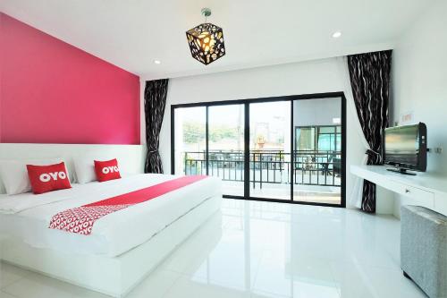 1 dormitorio con cama blanca y pared rosa en Tina Boutique Resort en Thalang