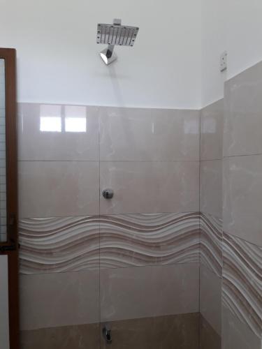 a shower with a glass door with a light on it at B & B CHARM in Dickwella