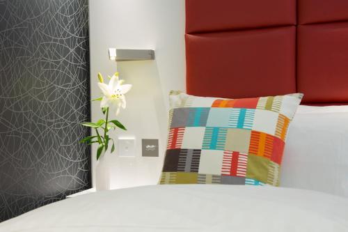 a bedroom with a bed with a pillow and a flower at Henley House Hotel in London