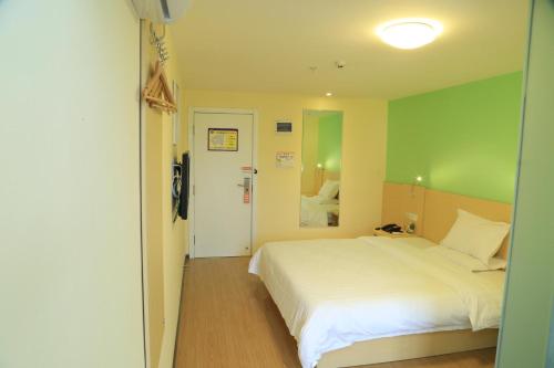 1 dormitorio con cama blanca y pared verde en 7Days Inn Guiyang Ergezhai, en Guiyang