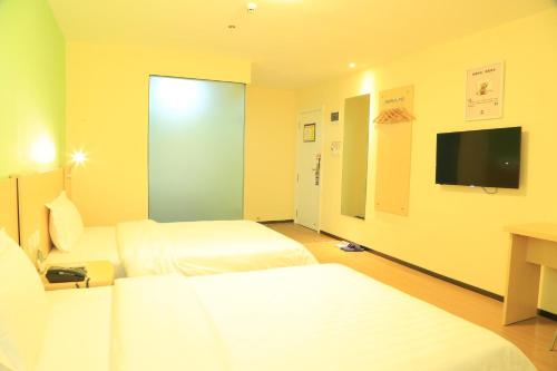 a hotel room with two beds and a flat screen tv at 7Days Inn Guiyang Ergezhai in Guiyang