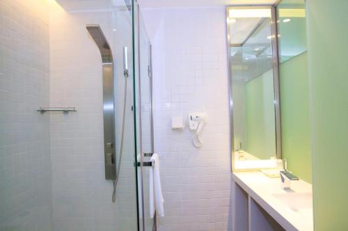 貴陽的住宿－7天酒店·贵阳北站店，带淋浴、盥洗盆和镜子的浴室