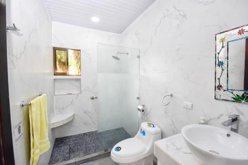 uma casa de banho branca com um lavatório e um WC em Casa Federico em Quepos
