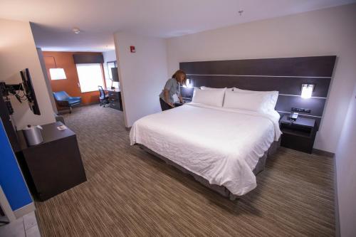 a woman standing next to a large bed in a hotel room at Holiday Inn Express & Suites Locust Grove by IHG in Locust Grove