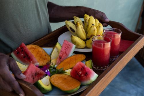 uma bandeja com um prato de frutas e dois copos de suco em Kudakalliya Beach House em Baía de Arugam