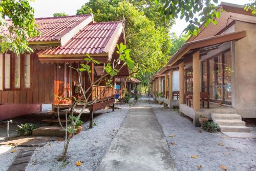 a row of wooden buildings with a pathway between them at Frog Beach House in Ko Phayam