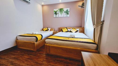two beds in a small room with wooden floors at Hoàng Gia Hotel Côn Đảo in Con Dao