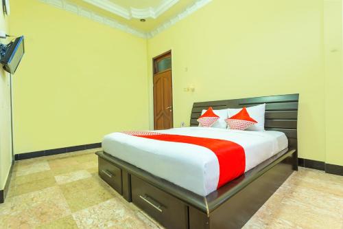 a bedroom with a large bed with red and white pillows at OYO 2848 Senaz Guesthouse in Mataram