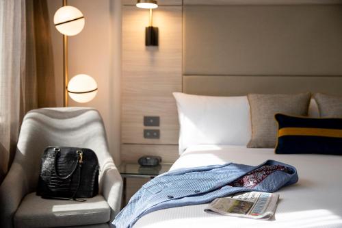 Habitación de hotel con cama, silla y libro en Novotel Sydney Parramatta en Sídney