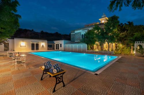 a large swimming pool in a backyard at night at The Udaibagh in Udaipur