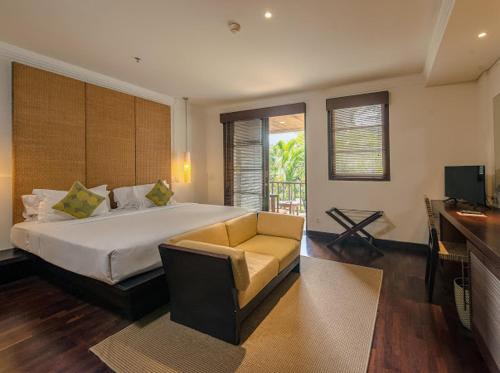 1 dormitorio con cama, sofá y TV en Ruby Nusa Dua Bali, en Nusa Dua