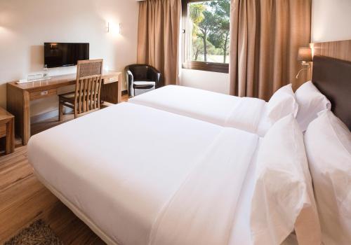 a hotel room with a large white bed and a desk at Hotel Eden Park by Brava Hoteles in Riudellots de la Selva