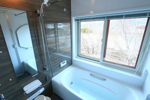 a bathroom with a tub and a window and a sink at SILVER SPRAY MtFuji view Yamanakako in Yamanakako