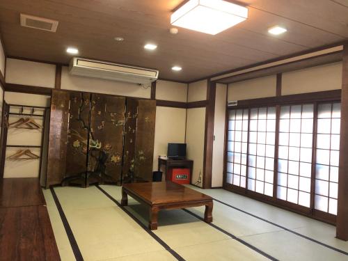 a room with a table in a room with windows at Takigawa Ryokan in Kyoto