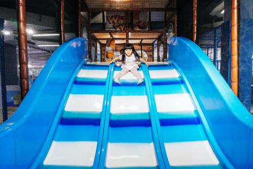 a little girl sitting on a slide at a playground at FuramaXclusive Ocean Beach Seminyak Bali in Legian