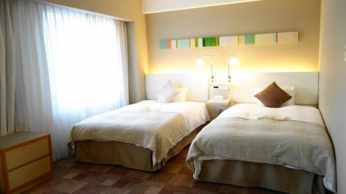 a hotel room with two beds and a window at City Plaza Osaka in Osaka