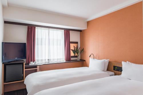 a hotel room with two beds and a television at the b nagoya in Nagoya