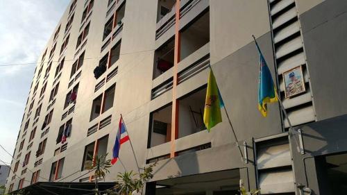 tres banderas están volando fuera de un edificio en Pacific Apt, en Bangna