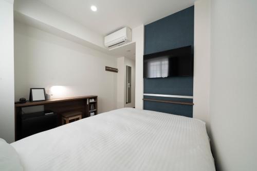 a bedroom with a white bed and a tv at washingtonR&B Hotel Sendai Higashiguchi in Sendai