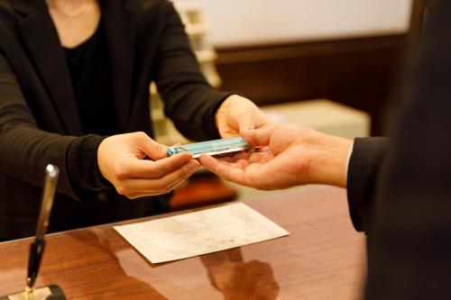 a person is handing another person a cell phone at Fukuno Town Hotel A・Mieux in Nanto