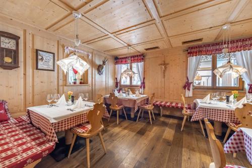 a dining room with tables and chairs and wooden walls at Almhotel Glieshof in Malles Venosta