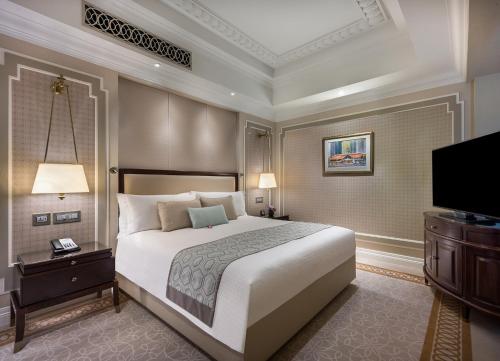 a bedroom with a large bed and a flat screen tv at The Fullerton Hotel Singapore in Singapore