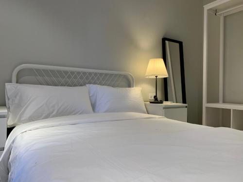 a bed with white sheets and a lamp and a mirror at Forest View Apartments in Kololi