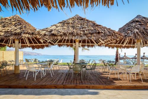 a beach with chairs and tables and umbrellas at Solimar White Pearl - Adults Only in Kolymvari