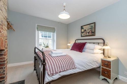 a bedroom with a large bed and a window at Oxfordshire Living - The Bowler Hat Cottage - Woodstock in Woodstock