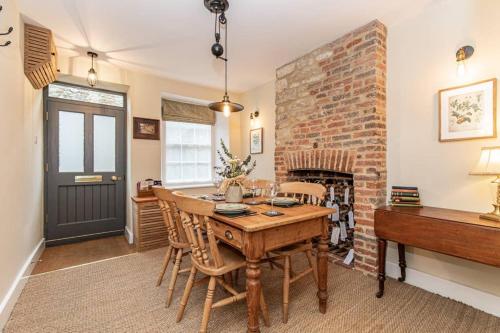 a dining room with a table and a brick wall at Oxfordshire Living - The Bowler Hat Cottage - Woodstock in Woodstock