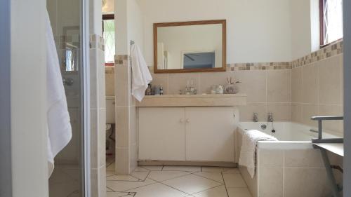 uma casa de banho com uma banheira, um lavatório e um espelho. em Lucky Fishes em Southbroom