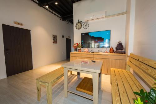 Zimmer mit einem Tisch, einer Bank und einem TV in der Unterkunft Xiaoliuqiu 88 Homestay in Xiaoliuqiu