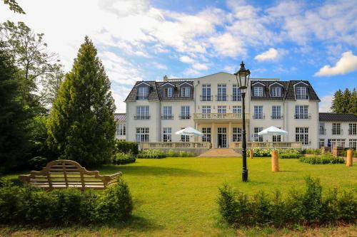 a large white building with a bench in front of it at The Starnbergsee Hideaway in Seeshaupt