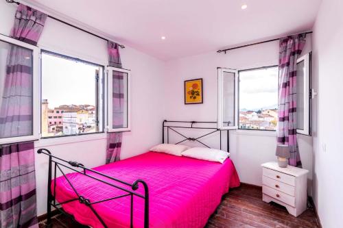1 dormitorio con 1 cama rosa y 2 ventanas en La Casa Con La Vista Delle Fortezze by CorfuEscapes, en Corfú