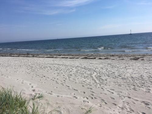 a beach with footprints in the sand and the ocean at ÅhusGården Stugor in Åhus