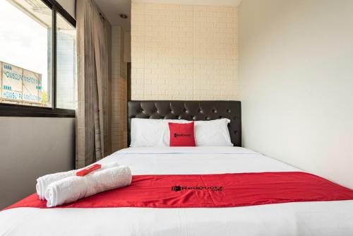 - une chambre avec un grand lit blanc et une couverture rouge dans l'établissement RedDoorz near Tanjung Duren 2, à Jakarta