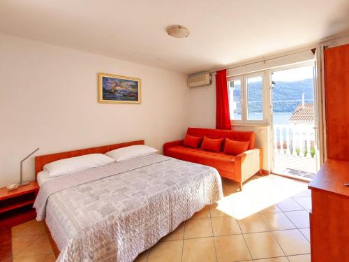 a bedroom with a bed and a chair and a window at Apartments Sentic in Neum