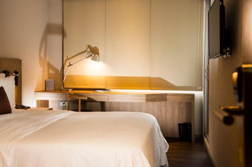 a bedroom with a white bed and a lamp at Just Sleep Kaohsiung Zhongzheng in Kaohsiung