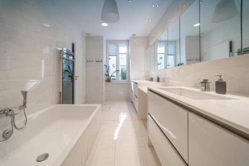 - une grande salle de bains blanche avec deux lavabos et une baignoire dans l'établissement Le Reflet du Lac, à Annecy