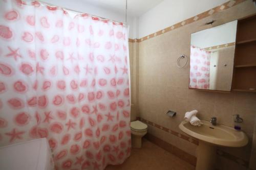 a bathroom with a shower curtain with a toilet and a sink at Meltemi in Xilosírtis