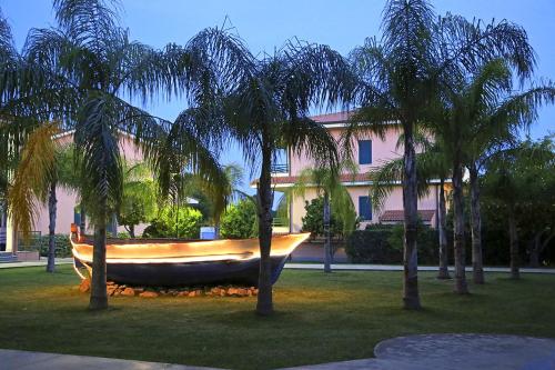 a boat sitting in the grass next to palm trees at Club Esse Aquilia Beach Village in Badolato