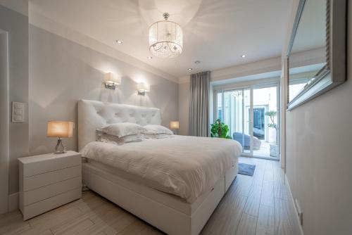 une chambre avec un grand lit et un lustre dans l'établissement Le Reflet du Lac, à Annecy