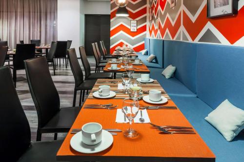 a long row of tables in a restaurant with orange table settings at Wyndham Bogota in Bogotá