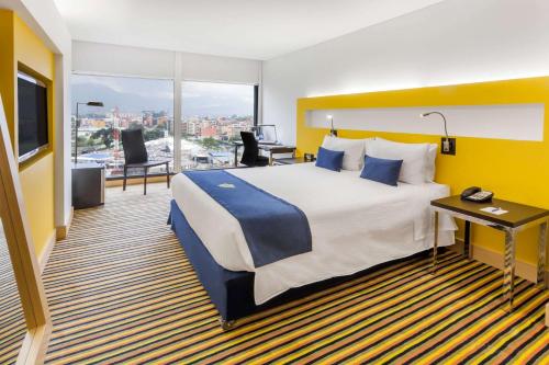 um quarto de hotel com uma cama grande e uma varanda em Wyndham Bogota em Bogotá