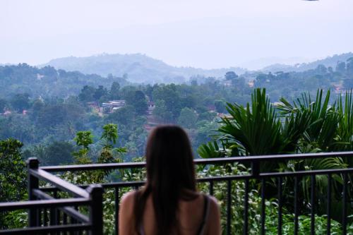 a woman sitting on a balcony looking at the mountains at Desire Village Rakwana in Rakwana