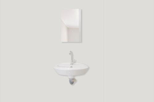 een badkamer met een witte wastafel en een spiegel bij OYO 2984 Berlian House Ungasan in Jimbaran